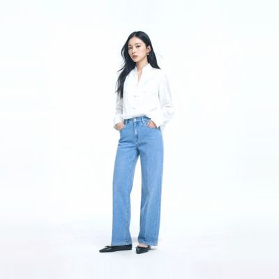 a woman standing in a white shirt and jeans