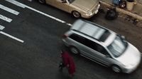 a man walking across a street next to parked cars