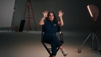 a woman sitting in a chair in front of a camera