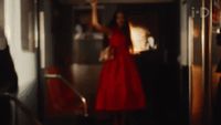 a woman in a red dress walking down a hallway