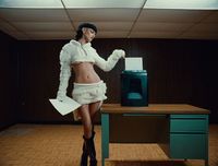 a woman in a white outfit standing in front of a desk