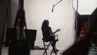 a woman sitting in a chair in front of a camera