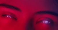 a close up of a person's eyes with a red background