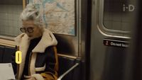 a woman sitting on a subway looking at her phone