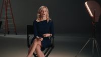 a woman sitting in a chair in front of a camera