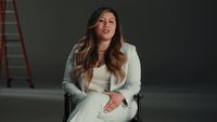 a woman sitting in a chair with a ladder behind her