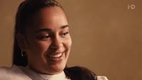 a woman smiling and wearing a white shirt and tie