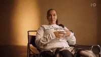 a woman sitting in a chair holding a glass