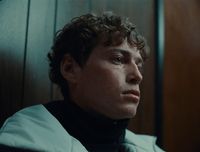 a man with curly hair wearing a black turtle neck sweater