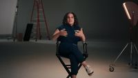 a woman sitting in a chair in front of a camera