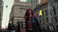 a woman with red hair walking down a city street