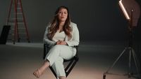 a woman sitting in a chair in front of a camera