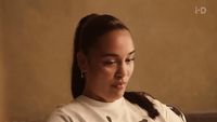 a woman sitting on a couch wearing a white shirt