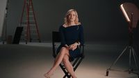 a woman sitting in a chair in front of a camera