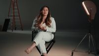 a woman sitting in a chair in front of a camera