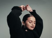 a woman in a black sweater is holding her hair up