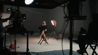 a woman sitting on a chair in front of a camera