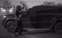 a man standing next to a parked car in a parking lot