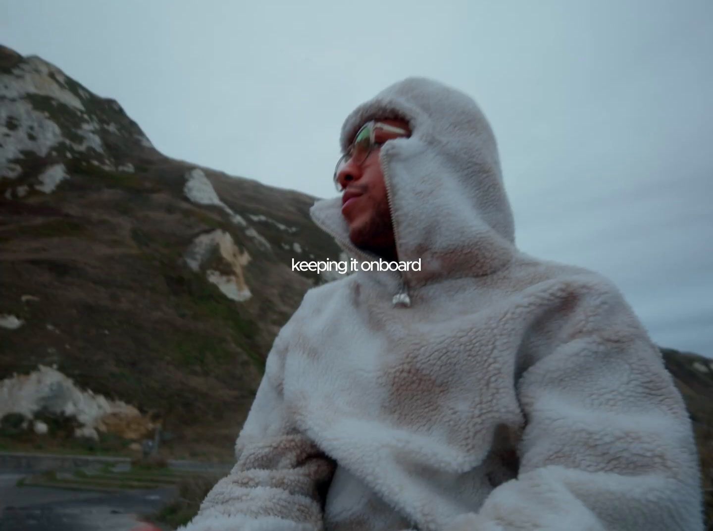 a man in a white outfit standing in front of a mountain