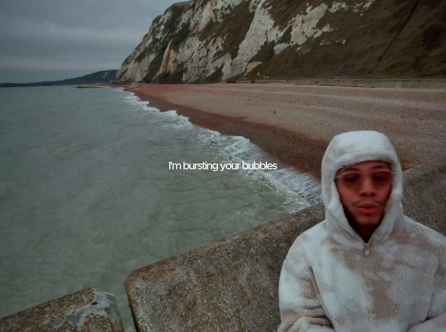 a man in a white hoodie standing next to a body of water