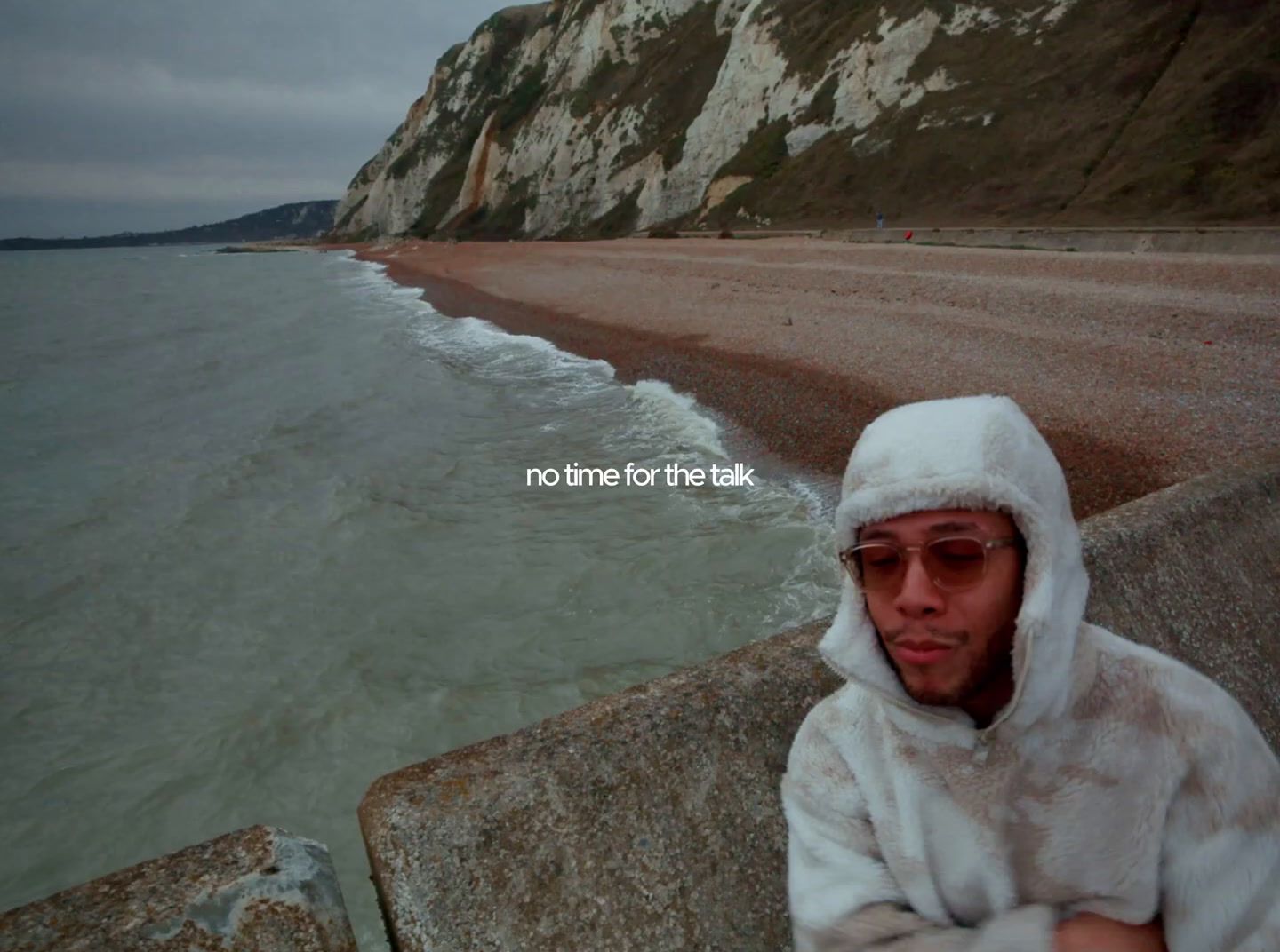 a man in a hooded jacket standing on a beach