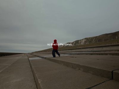 a man in a red jacket is walking on concrete