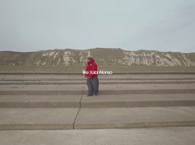 a person in a red jacket standing on concrete steps