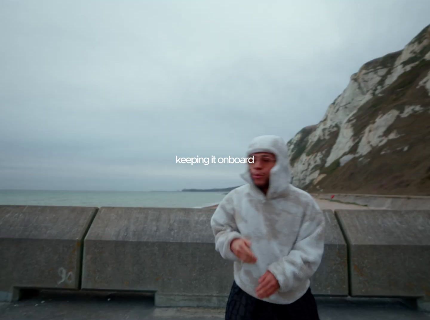 a man in a white jacket standing in front of a body of water