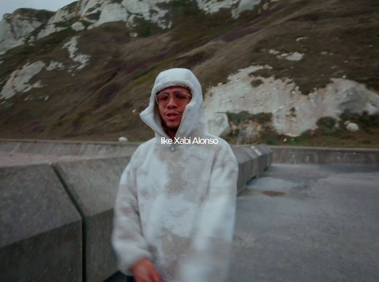 a man in a white robe is standing in front of a mountain