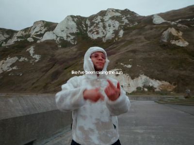 a man in a hoodie standing in front of a mountain