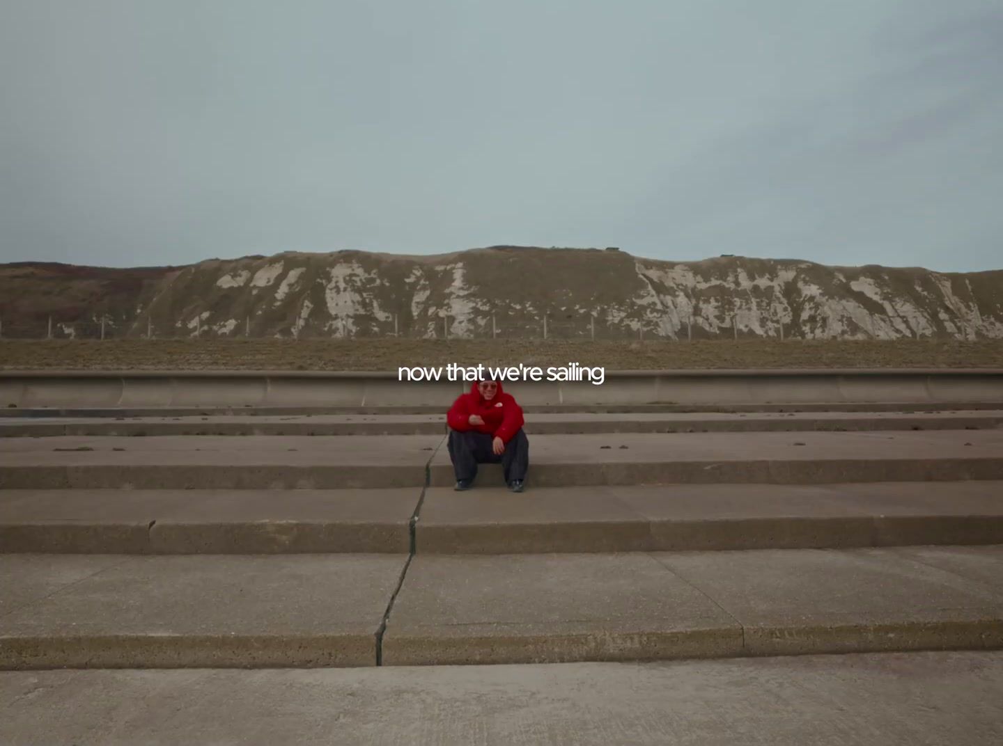 a man sitting on a cement step in front of a mountain