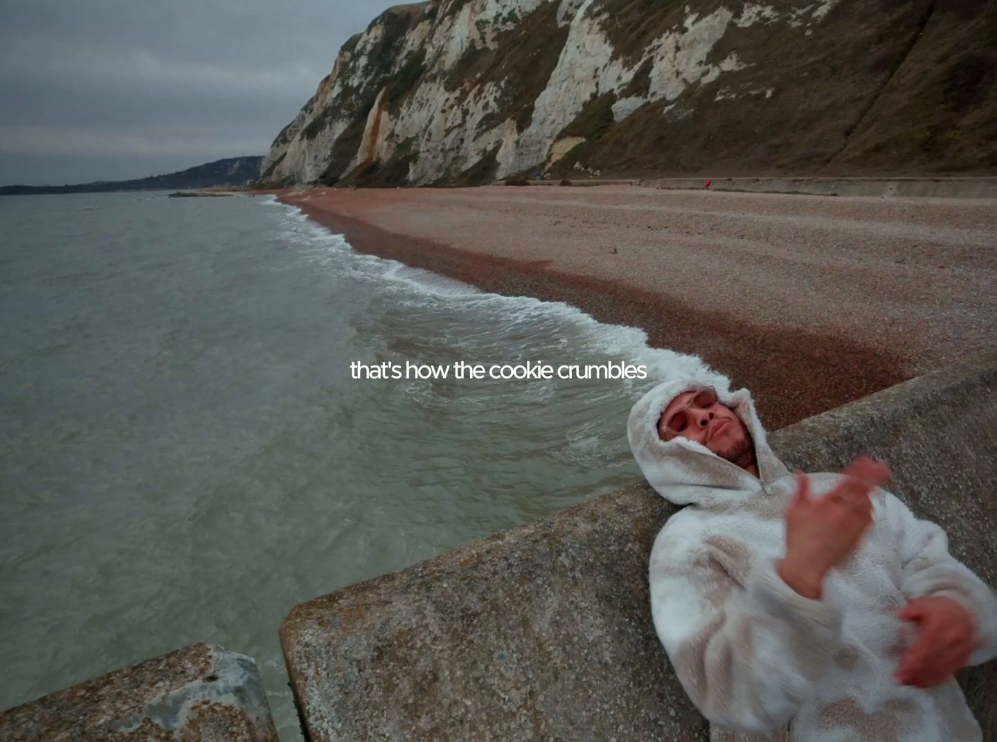 a baby wrapped in a blanket on a beach next to the ocean