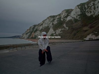 a person in a white hoodie standing in front of a body of water