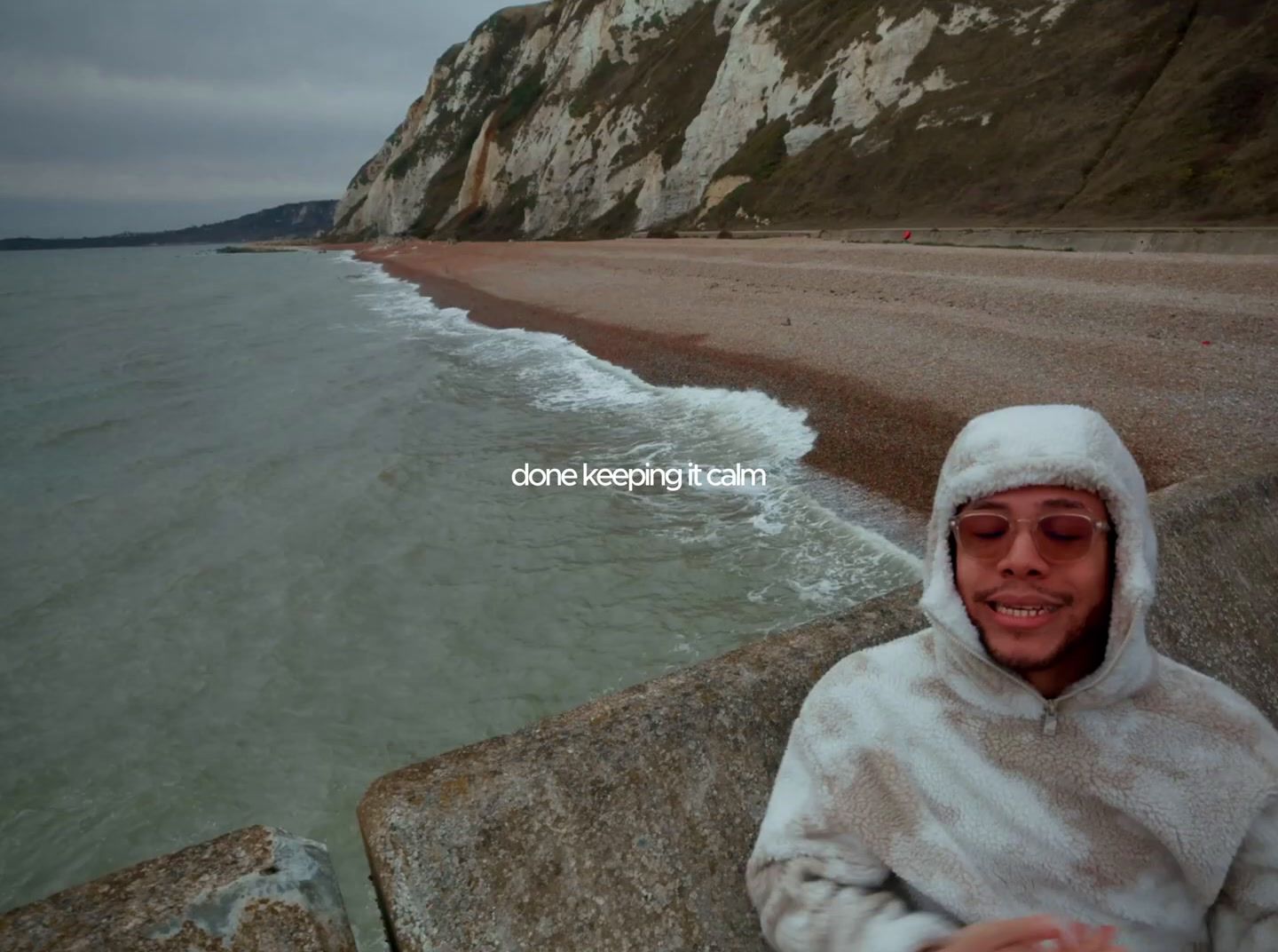 a man in a hooded jacket standing next to a body of water