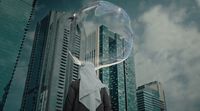 a person standing in front of a tall building with a bubble in their mouth