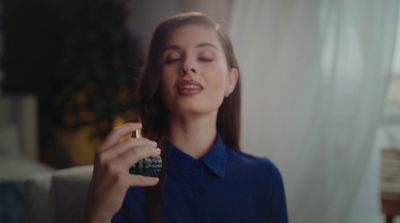 a woman in a blue shirt is holding a cell phone