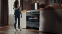 a woman standing in front of an oven in a kitchen