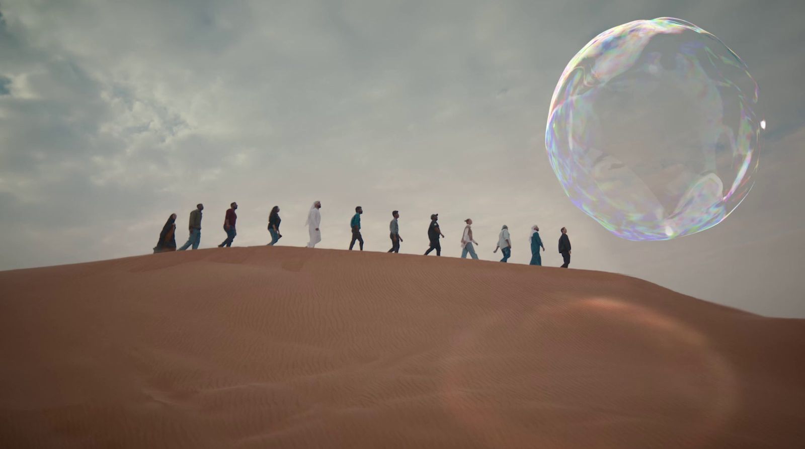 a group of people standing on top of a sand dune