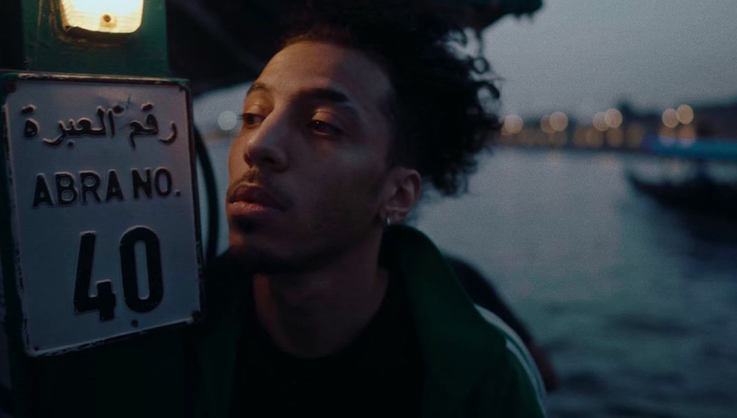 a man standing next to a street sign in front of a body of water