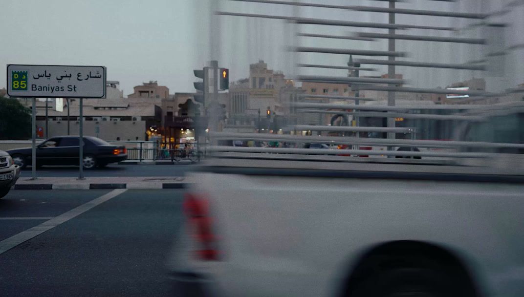 a white truck driving down a street next to tall buildings