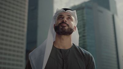 a man wearing a white headdress in front of tall buildings