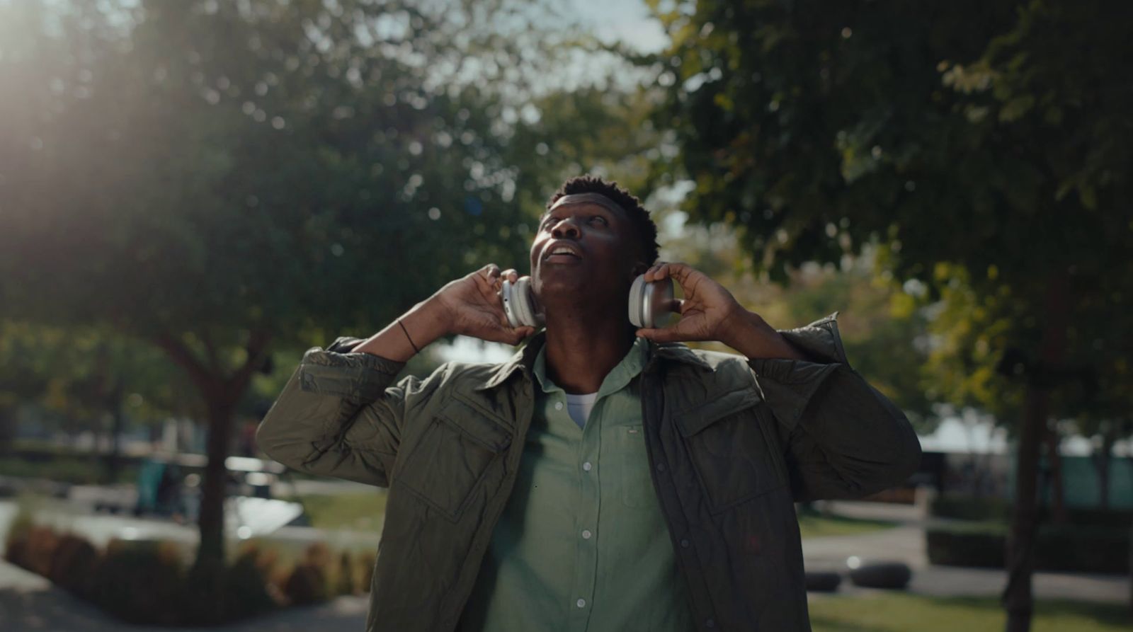 a man talking on a cell phone while standing in a park