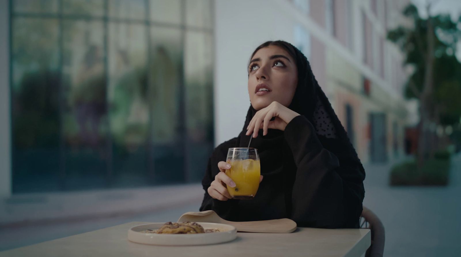 a woman sitting at a table with a glass of orange juice