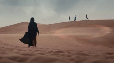 a group of people walking across a desert