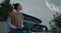 a woman sitting on a bench looking up at a bubble