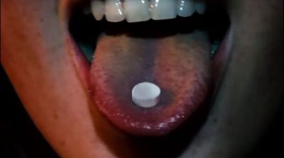 a close up of a person's mouth with a pill in it