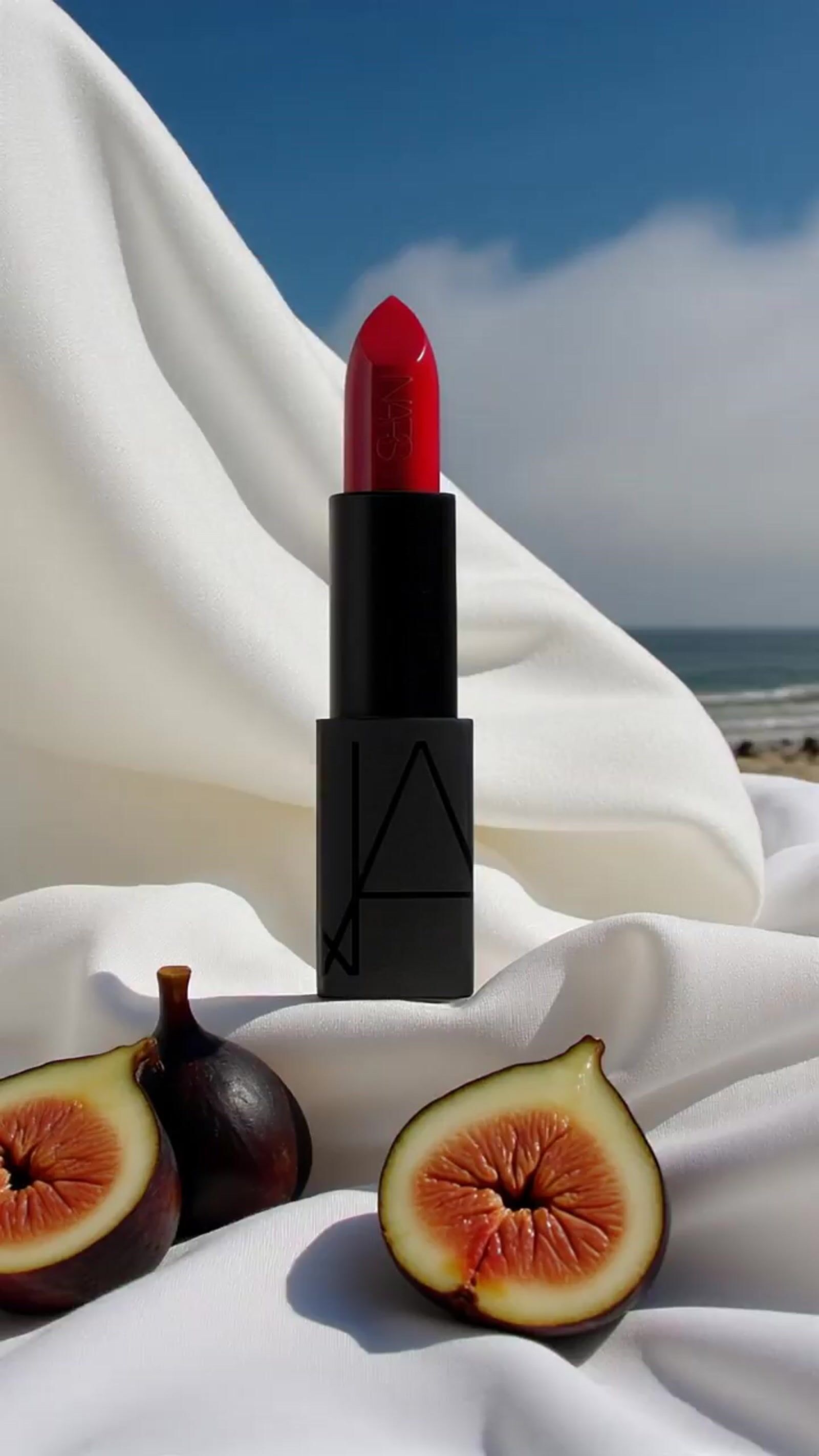 a lipstick and a fig on a white sheet