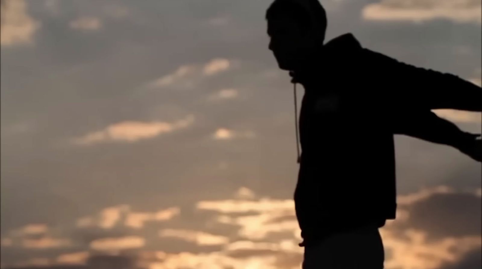 a silhouette of a man holding a skateboard