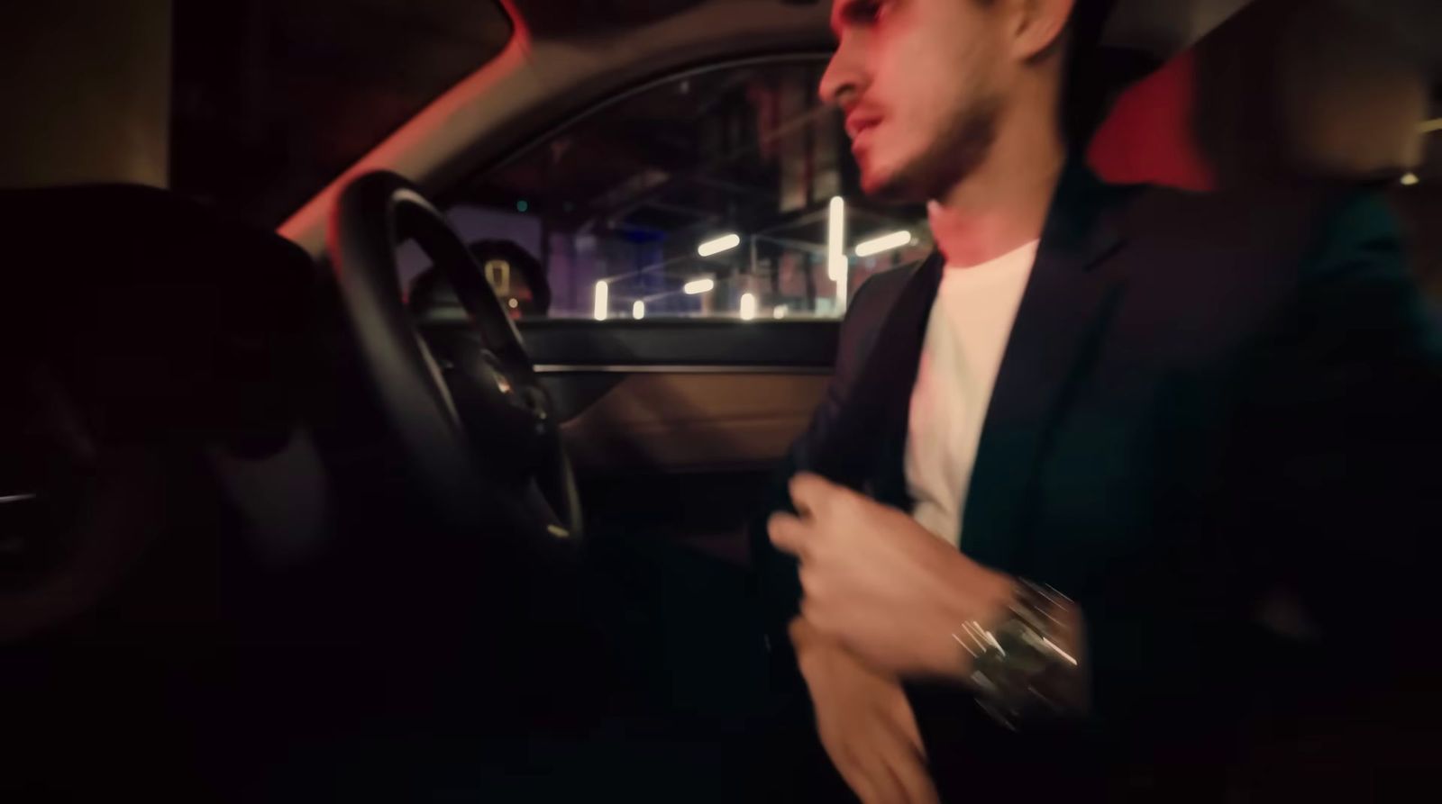 a man sitting in a car with his hand on the steering wheel