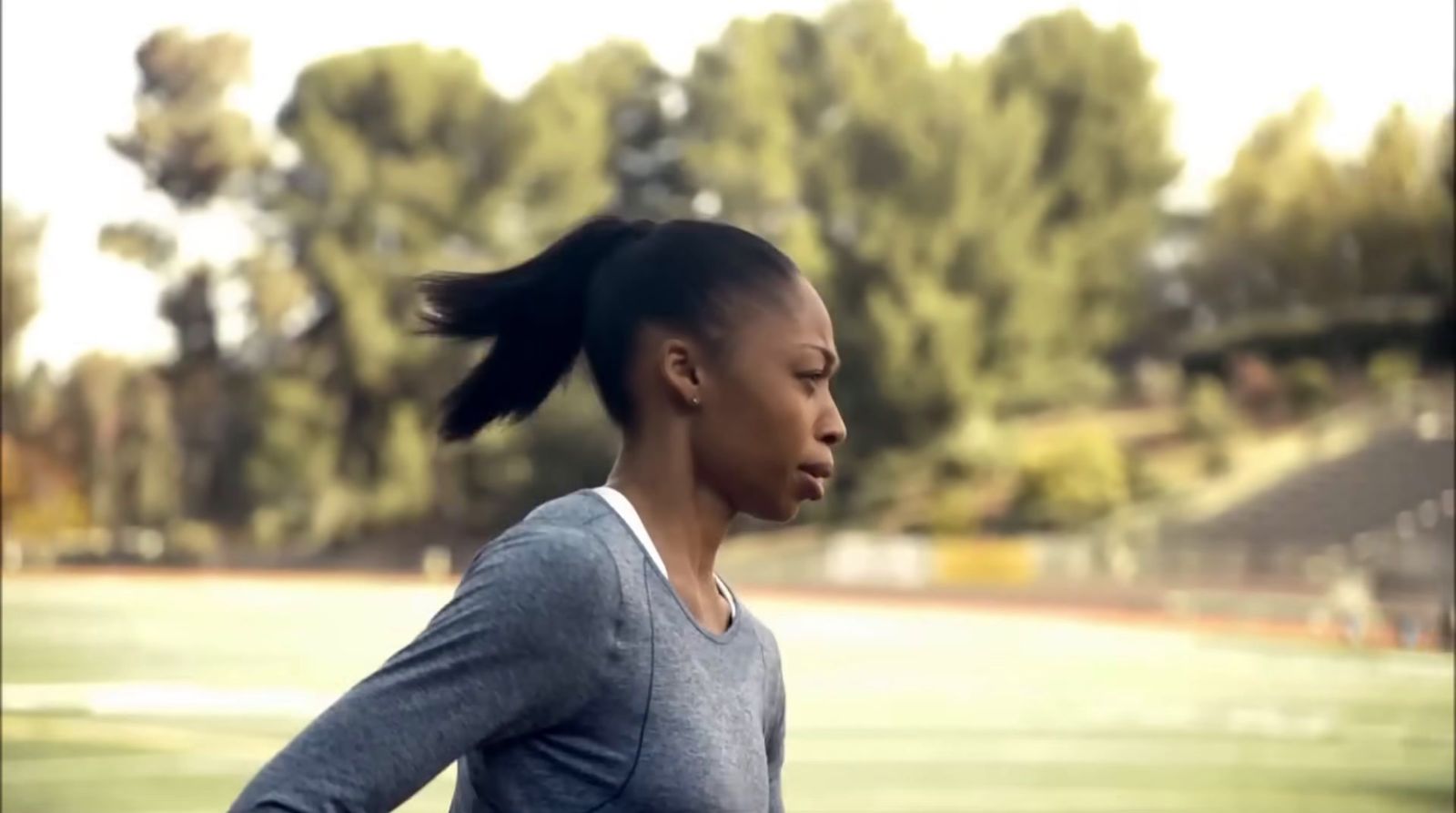 a woman with a ponytail standing in front of a soccer field